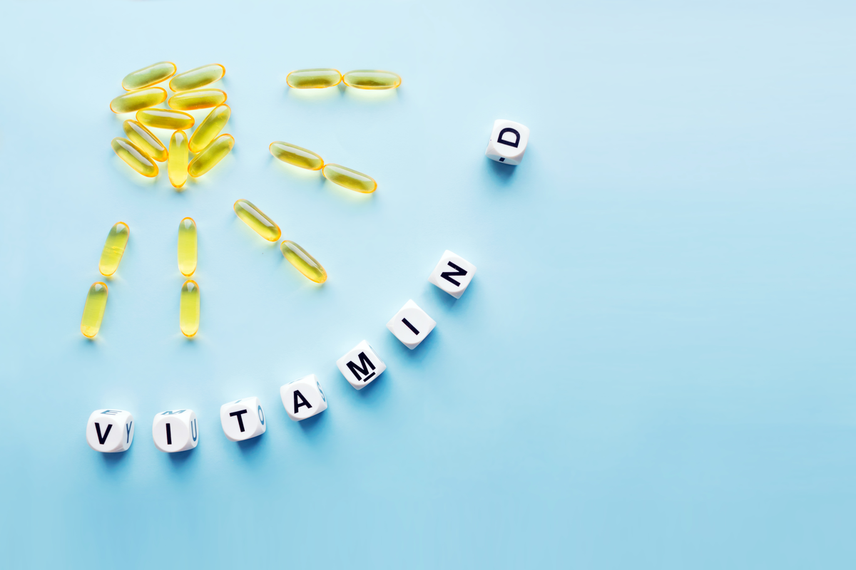 Vitamin D pills in shape of sun with vitamin d letters outlining it on blue background