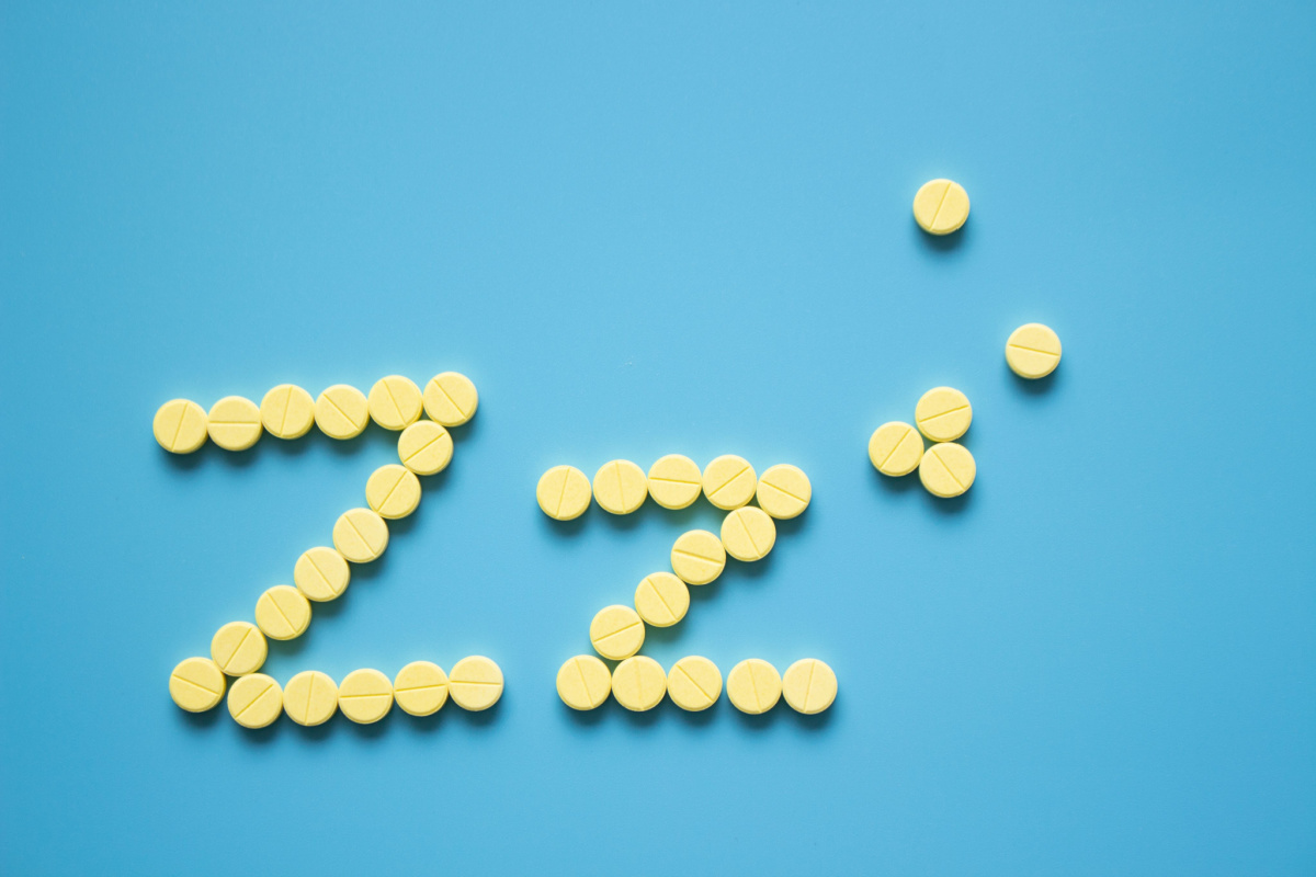 Round yellow pills in the shape of Z's on blue background